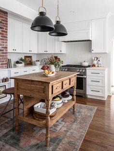 a kitchen with two hanging lights over the island and an area rug on the floor