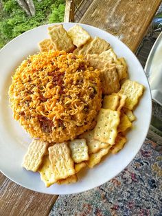 a white plate topped with cheese crackers and other food on top of a wooden table