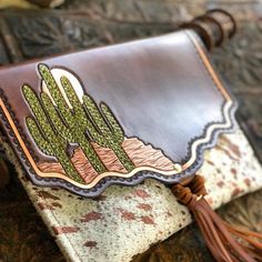 a brown leather purse sitting on top of a piece of cloth with tassels