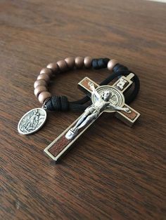 a rosary with a cross on it and a black beaded bracelet is laying on a wooden table