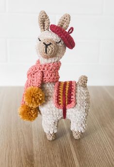 a crocheted llama with a red hat and scarf on it's back