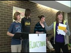 some people are standing in front of a brick wall and one is holding a sign