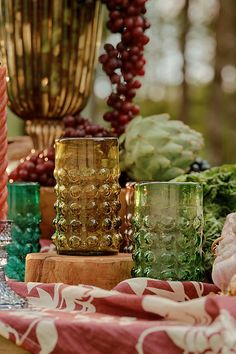 a table topped with lots of different colored glasses and candles next to each other on top of a wooden table