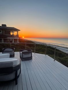 the sun is setting over the ocean and some chairs are set up on the deck