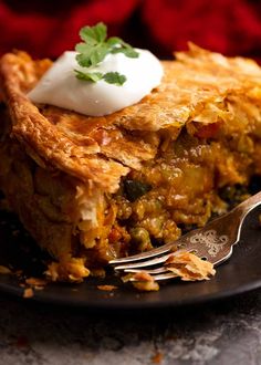 a piece of pie on a black plate with a fork and garnishes