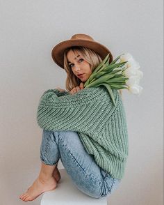 a woman sitting on top of a white stool holding a bouquet of tulips