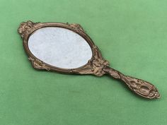 an antique looking mirror sitting on top of a green surface