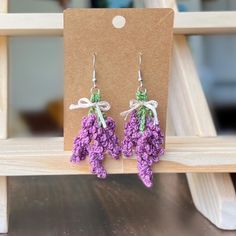 small purple flowers are hanging from the back of a wooden bench with a tag attached to it