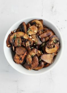 a white bowl filled with mushrooms on top of a table