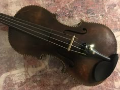 an old violin sitting on top of a table next to a wallpaper covered floor