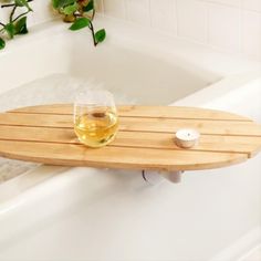 a glass of wine sitting on top of a bath tub next to a wooden tray