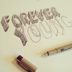 a pen sitting on top of a piece of paper with the words forever young written in it