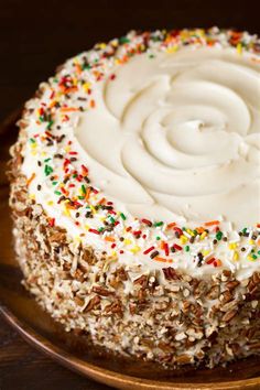 a cake with white frosting and sprinkles on a wooden platter