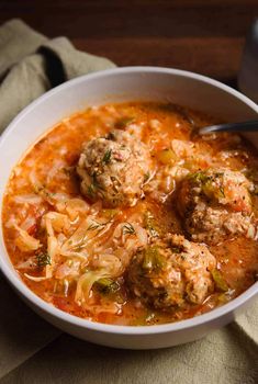 a white bowl filled with meatballs and vegetable soup