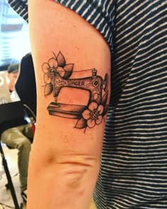 a woman's arm with a sewing machine tattoo on it