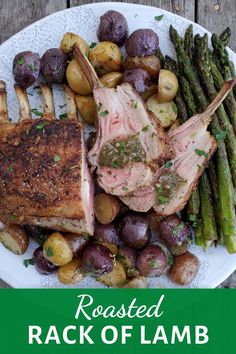 roasted rack of lamb with potatoes and asparagus on a white plate over a wooden table