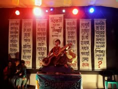 a man that is sitting on top of a table with a guitar in front of him