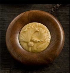 a wooden necklace with a carved medallion in the center on a dark surface, featuring an image of a woman's head