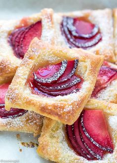 small desserts with powdered sugar and fruit toppings are arranged on a plate