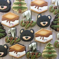 decorated cookies are arranged on a table with pine trees and bear decorations in the background