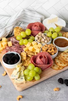 an assortment of cheeses, meats and crackers on a wooden platter