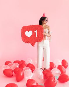 a woman standing in front of balloons holding a sign with the number one on it