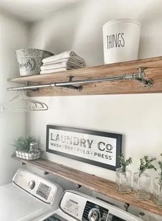 a white washer and dryer sitting in a room next to a wooden shelf