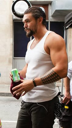 a man in white tank top and black shorts holding a can of drink while standing next to a woman