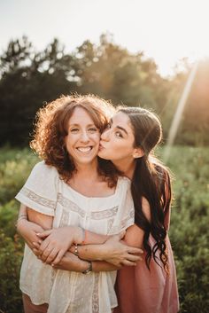 two women hugging each other in the middle of a field