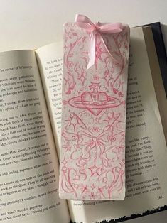 an open book with pink ink on it and a ribbon tied to the cover in front