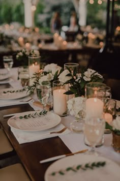 the table is set with white flowers and candles for an elegant dinner party or wedding reception