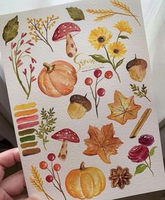 a person holding up a card with autumn leaves and mushrooms on it