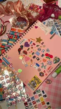 a pink notebook with lots of stickers on top of it next to other items