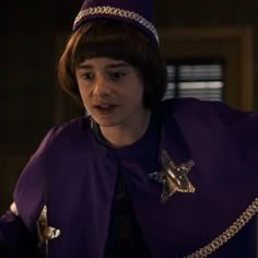 a young boy dressed in a purple outfit with a star on it's chest