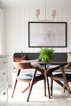 a dining room table with chairs and a plant in the center surrounded by white paneled walls