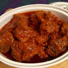 a white bowl filled with meat covered in sauce