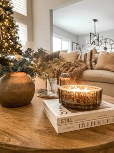 a living room with a christmas tree and candles on the coffee table in front of it