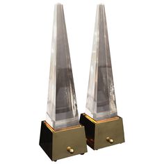 two clear glass and brass bookends sitting side by side