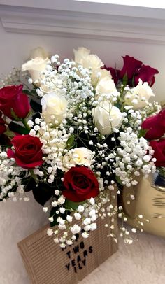 a vase filled with white and red roses on top of a table next to a box