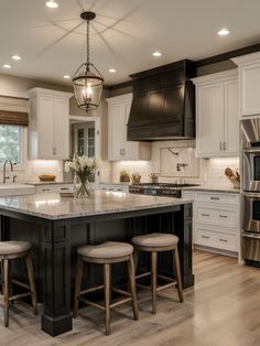 a large kitchen with an island in the middle and three stools at the end