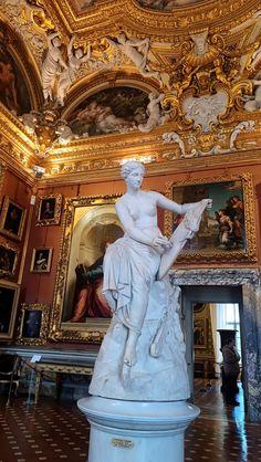 a statue in the middle of a room with paintings on the walls and ceiling above it