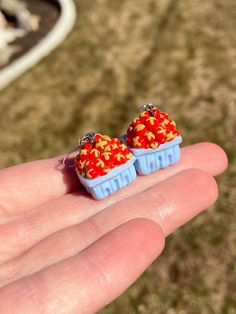 two tiny red and yellow candies sitting in small blue containers on someone's hand