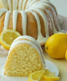 a lemon bunt cake with white icing on a plate next to sliced lemons