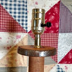 an old fashioned sewing machine sitting on top of a piece of wood in front of a quilt