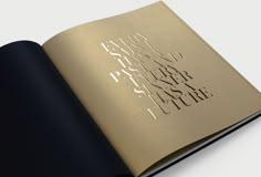 an open book with gold foil on the cover and black paper in front of it