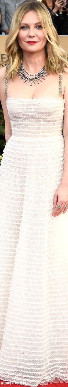 a woman in a white dress posing on the red carpet with her hands behind her head