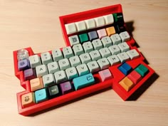 a red and white keyboard sitting on top of a wooden table