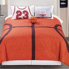 a bed with an orange and black basketball themed comforter set on top of it