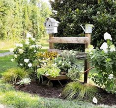 a garden filled with lots of flowers and plants next to a wooden bench in the grass