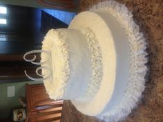 a three tiered cake with white ruffles and the number 60 on top